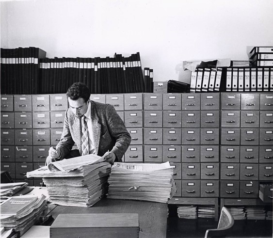 “RFE researcher checks new information against the record. The bank of filing cabinets which reaches from the wall through the eighth cabinet contains information on living conditions and individuals in Czechoslovakia.” RFE Public Affairs Photographic Files, Blinken OSA.